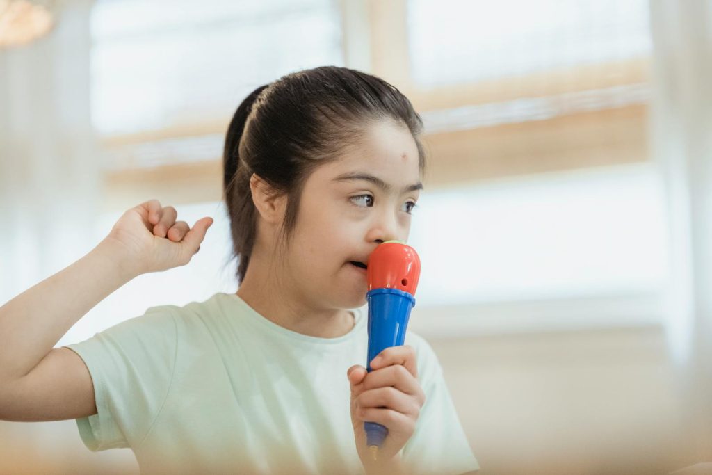 Young girl singing into a toy microphone, expressing joy and creativity indoors.